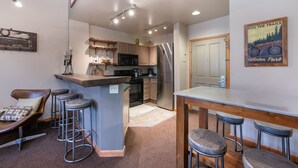 A compact kitchen with a central island, bar stools, and a dining table. - Zephyr Mountain Lodge, Condo | Ski Storage (Select-Rated Condo 2700) (Winter Park)