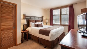 A hotel room with a large bed, a desk with a computer, a TV, and a window with curtains. - Zephyr Mountain Lodge, Condo | Balcony Slopes View (Select-Rated Condo 1620) (Winter Park)