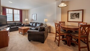 A living room with a sofa, a coffee table, a TV, a dining table with chairs, and a lamp. - Zephyr Mountain Lodge, Condo | Balcony Slopes View (Select-Rated Condo 1620) (Winter Park)
