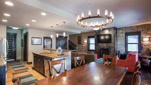 A spacious kitchen with a central island, a dining area with a large wooden table, and a cozy living room with a fireplace. - Village View, Townhouse | Fireplace at Parry Peak Lofts (Premium-Rated Condo 106) (Winter Park)