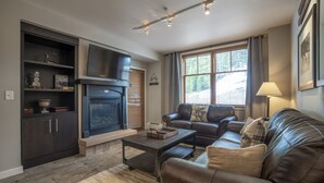 Una sala de estar con chimenea, sofá de cuero y televisor.