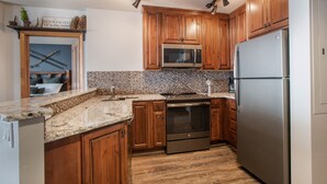 Una cocina con armarios de madera, un refrigerador de acero inoxidable, un microondas y un horno.