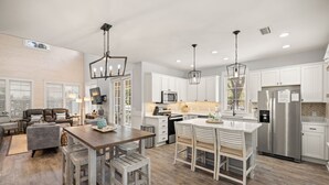 Une cuisine moderne avec des meubles blancs, des appareils en acier inoxydable et un coin repas en bois.