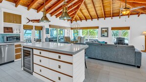 A spacious kitchen with a central island, wooden ceiling beams, and a view of the outdoors. - 5BR/4.5BA • Ocean Views • Pool & Hot Tub • Dock • Kayaks • Bikes & More (Key Largo)
