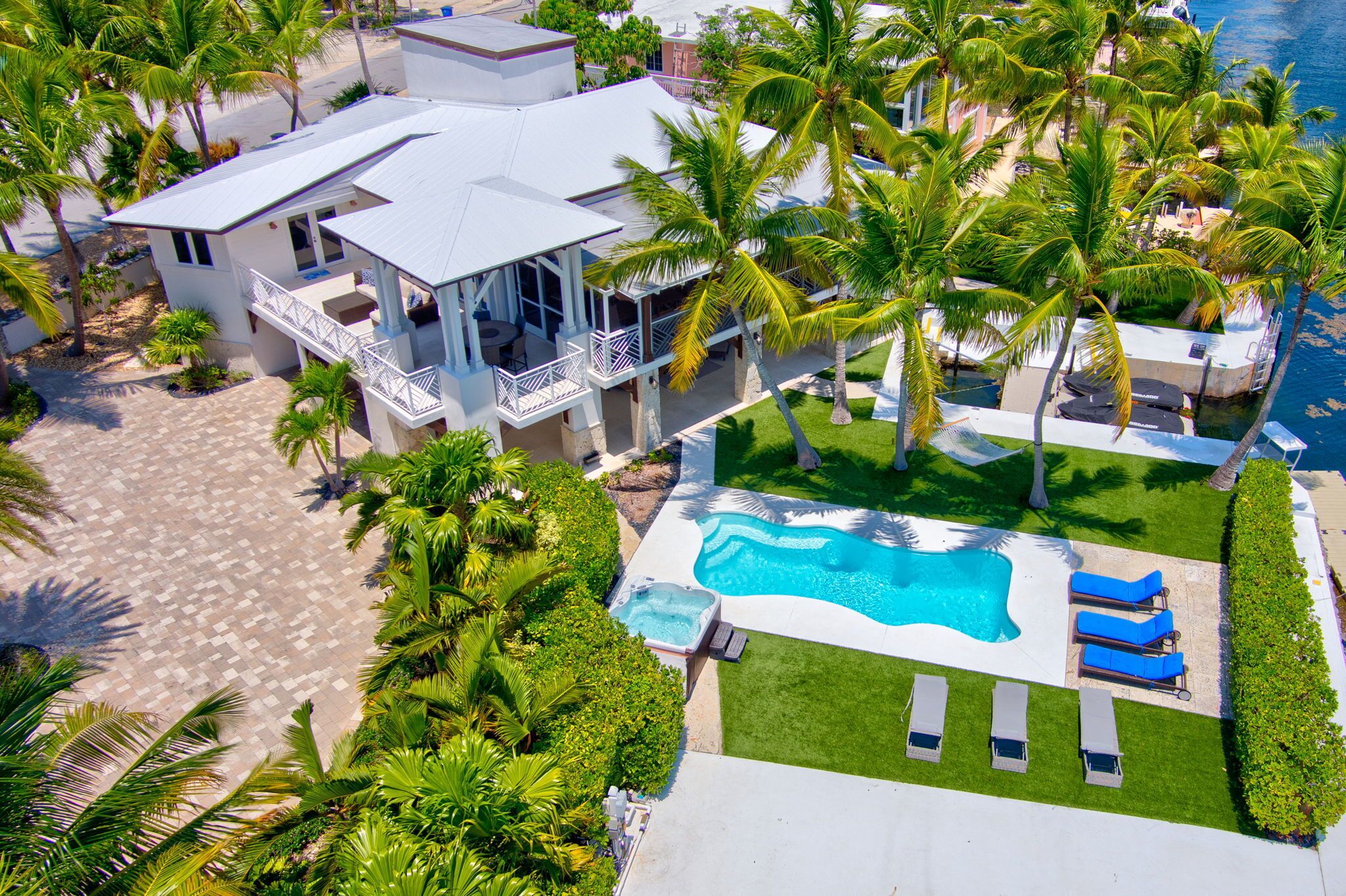 A large house with a swimming pool, multiple balconies, and a well-maintained lawn.