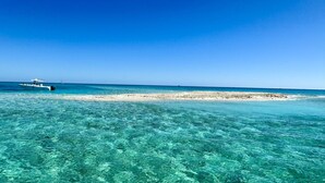 A clear view of a beach with a boat in the distance and a sandy area in the middle of the water. - 5BR/4.5BA • Ocean Views • Pool & Hot Tub • Dock • Kayaks • Bikes & More (Key Largo)