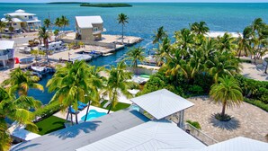 A resort with a marina, palm trees, and a view of the ocean. - 5BR/4.5BA • Ocean Views • Pool & Hot Tub • Dock • Kayaks • Bikes & More (Key Largo)