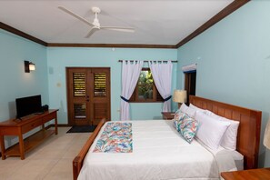 Ein Schlafzimmer mit Bett, Schreibtisch, Fernseher und Deckenventilator.