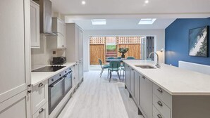 A modern kitchen with built-in appliances, a dining area with chairs, and a view of the outdoors. - Host & Stay | Iburn House (Briggswath)