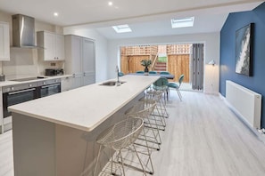 A modern kitchen with a central island, bar stools, and a view of a wooden deck.
