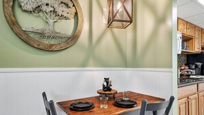 A dining area with a wooden table, chairs, a wall-mounted lantern, and a bear figurine. - Lovely condo w/ indoor pool *only steps to parkway (Gatlinburg)