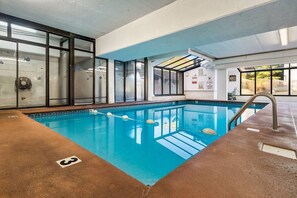 An indoor swimming pool with clear water, a diving board, and a lifeguard station.