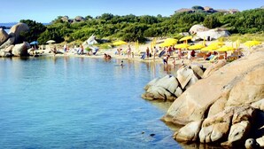A beach with clear water, rocks, and people.