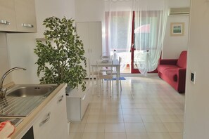 Una cucina moderna con lavello, pensili e una zona pranzo con tavolo e sedie.