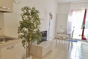 Una cocina moderna con un lavamanos, una zona de comedor con mesa y sillas, y una planta en maceta.