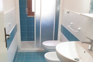 Un baño con azulejos azules, un lavamanos blanco y un inodoro.