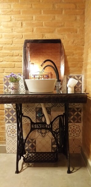 A kitchen sink with a modern faucet, a potted plant, and a decorative tile backsplash. - La Villa Chalés (SP)