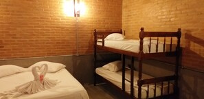 A room with two bunk beds, a brick wall, and a wall-mounted light fixture. - La Villa Chalés (SP)