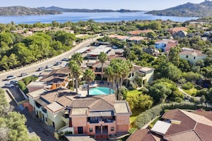 Vista aérea de una zona residencial costera con casas, una piscina y una carretera.