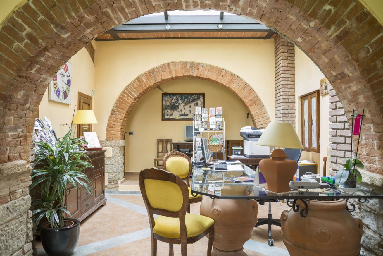A cozy interior with a brick archway, a glass table, a yellow chair, and a potted plant.