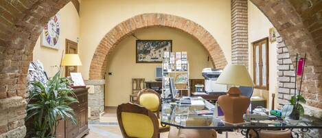 A cozy interior with a brick archway, a glass table, a yellow chair, and a potted plant.