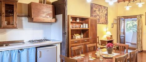 A rustic kitchen with wooden cabinets, a gas stove, and a dining area with a wooden table and chairs.