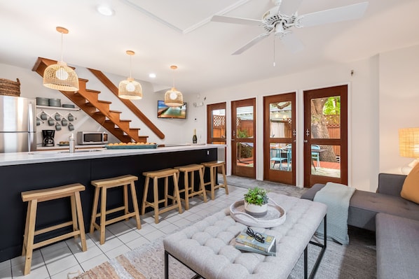 Uma cozinha moderna com ilha central, banquetas de madeira e um espaço de bar.