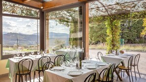 An outdoor dining area with tables set for two, large windows offering a view of the countryside, and a wooden ceiling structure. - Villa Grassina Quadrilocale sleeps 8, WIFI, pool, Nature (Pelago)