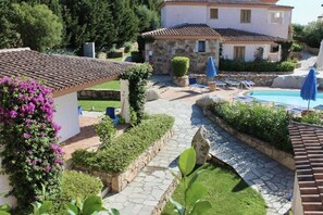 A villa with a stone pathway, a swimming pool, and a garden with a pergola and blue umbrellas. - Two-room apartment with 4 beds, about 30/37 sq m, living room with kitchenette and twin sofa bed, bedroom with double bed, bathroom with shower. Possibility 1 infant in cot. <br>Finely furnished apartments are arranged on the ground floor with a patio or (Budoni)