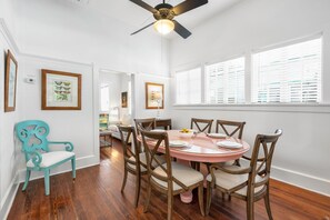 A dining area with a round table, wooden chairs, and a ceiling fan.