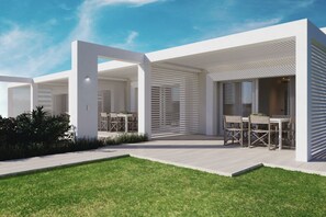 A modern outdoor patio area with a minimalist design, featuring a flat roof, white walls, and a well-maintained lawn.