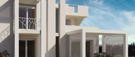 A modern two-story house with a flat roof, large windows, and a covered patio area.