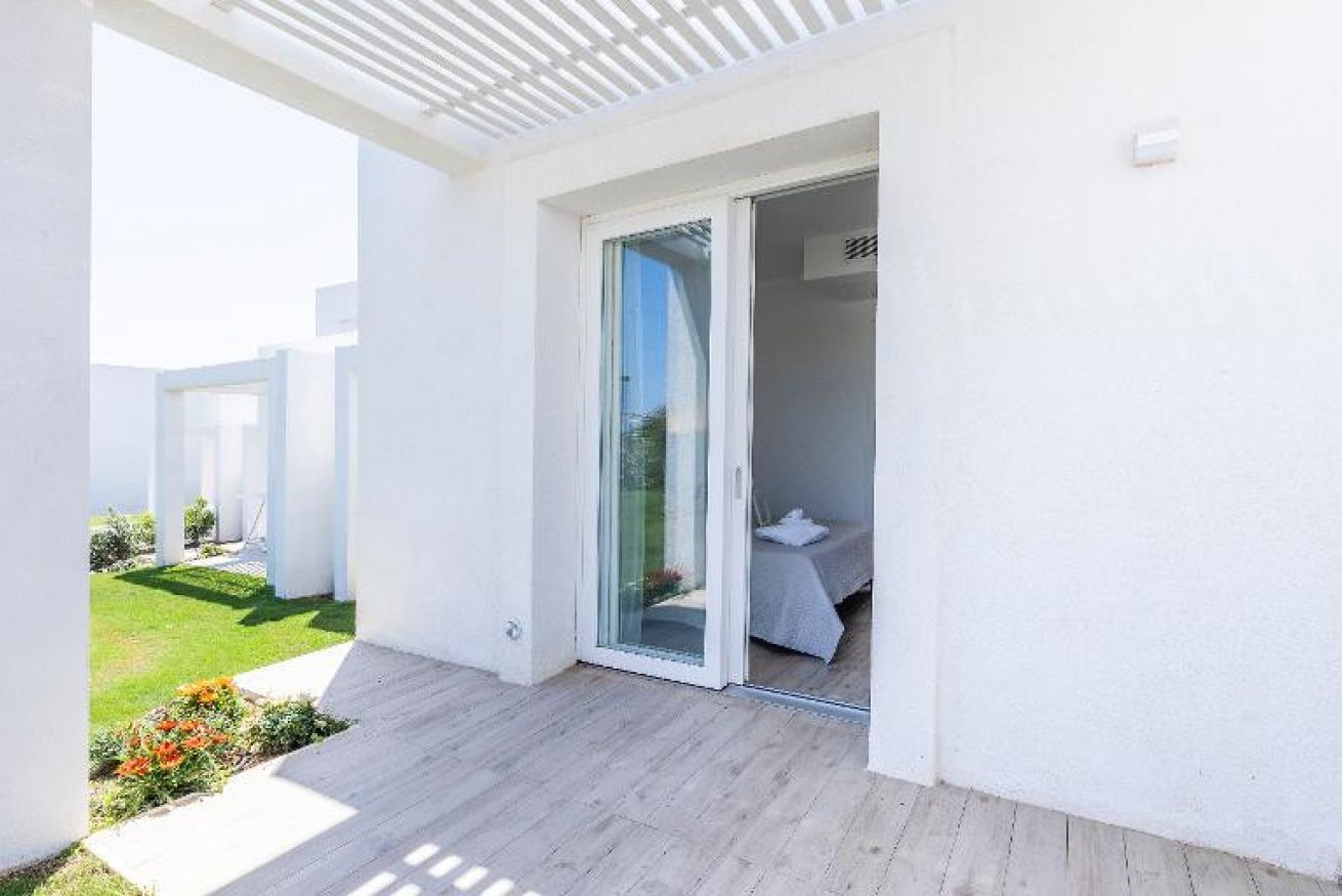 A modern outdoor balcony with a sliding glass door leading to a bedroom.