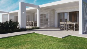 Un patio exterior moderno con diseño minimalista, que cuenta con techo plano, paredes blancas y un césped cuidado.