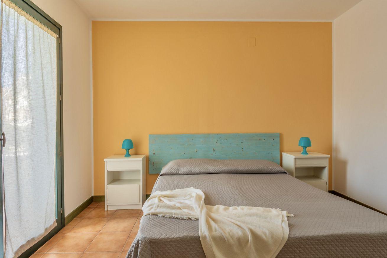 Een slaapkamer met een bed, twee nachtkastjes en een raam met gordijnen.