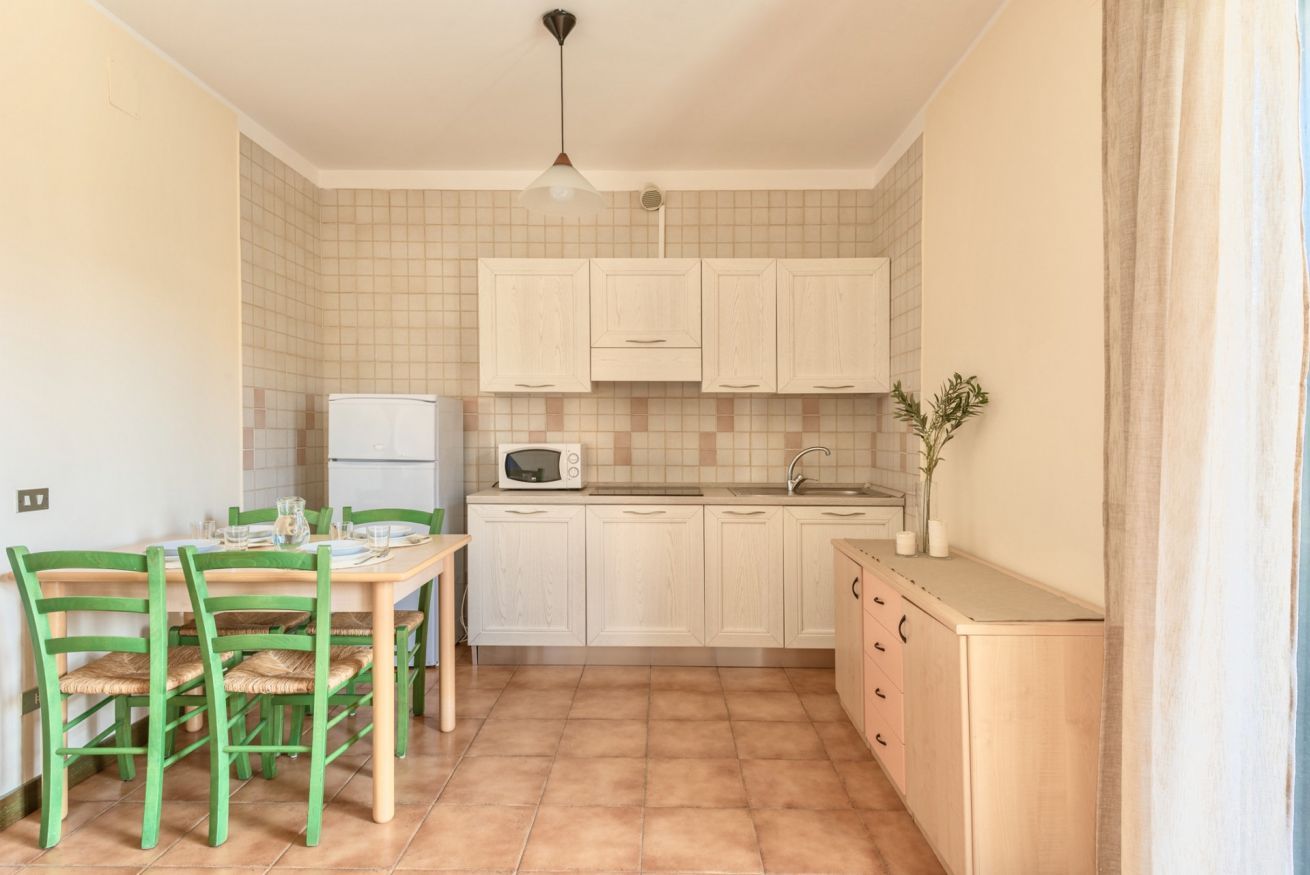 Una cocina compacta con comedor, que incluye microondas, lavamanos y armarios.