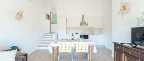 A compact living space with a dining area, kitchenette, and a TV on a wooden cabinet.
