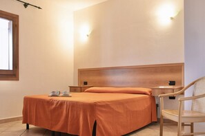Ein Schlafzimmer mit einem Bett, einem Sessel, einem Nachttisch und einem Fenster.