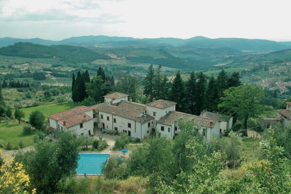Une villa comprenant plusieurs bâtiments, une piscine et offrant une vue sur des collines et des montagnes.