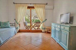 Una habitación con cama, televisión, mesa de comedor con sillas y vistas al exterior.