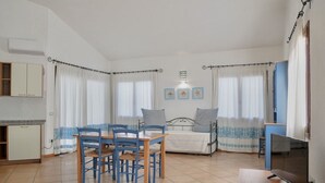 Ein Zimmer mit Esstisch, Stühlen, einem Bett, einem Fernseher und einer Küchenzeile.