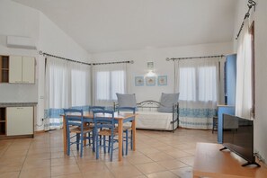Una habitación con una mesa de comedor, sillas, una cama, un televisor y un kitchenette.