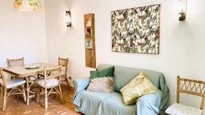 Quarto com uma mesa de jantar e cadeiras, um sofá e um quadro pendurado na parede.