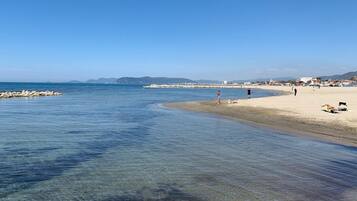 Una spiaggia con acque cristalline, una riva sabbiosa e alcune persone che passeggiano.
