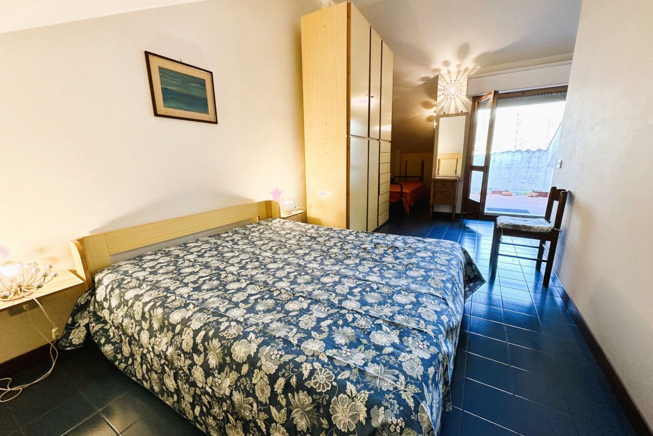 A bedroom with a bed, a wardrobe, a chair, and a desk.