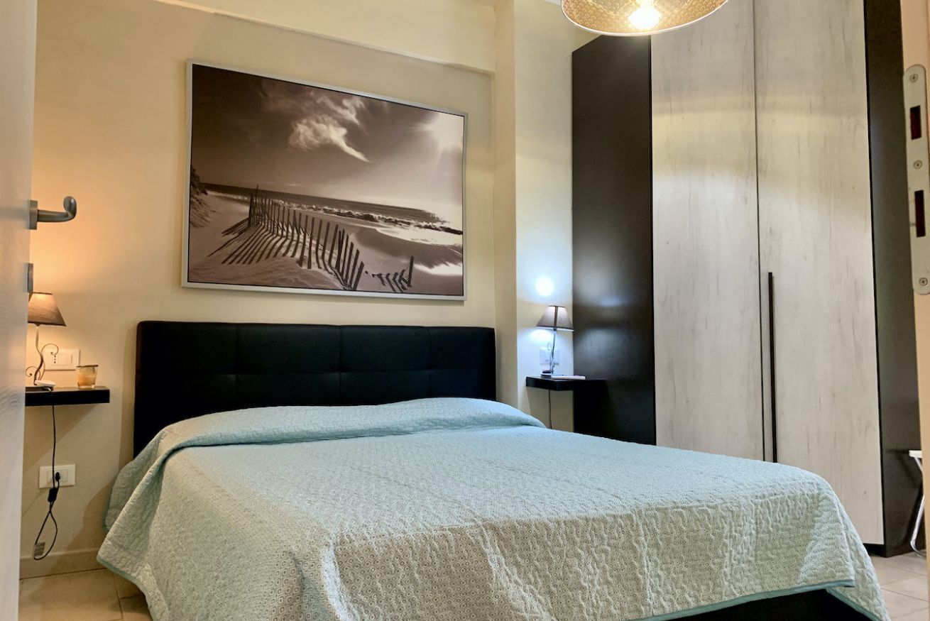 Una camera da letto con un letto, un'opera d'arte appesa al muro, lampade sui comodini e un armadio.