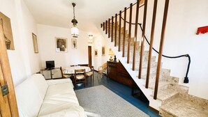A spacious living area with a white sofa, a dining table, and a staircase with wooden railings. - Apartment 3 rooms furnished with taste, 55/60mq, kitchenette / living room and double sofa bed or two sofa beds, matrimonial bedroom, double bedroom, bathroom.Included of:<br>tv, <br><b>washing machine<b>, <br><b>balcony or small garden <b>, <br>parking  (Massa)