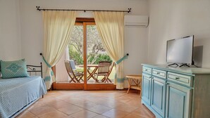 Una stanza con un letto, una televisione, un tavolo da pranzo con sedie e vista sull'esterno.