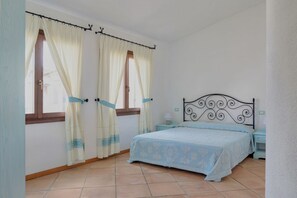 A bedroom with a bed, curtains, a nightstand, and a window.