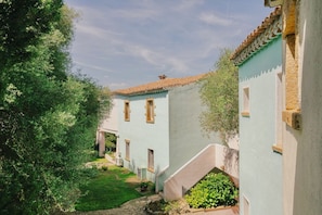 A courtyard with a building featuring a tiled roof and light-colored walls.